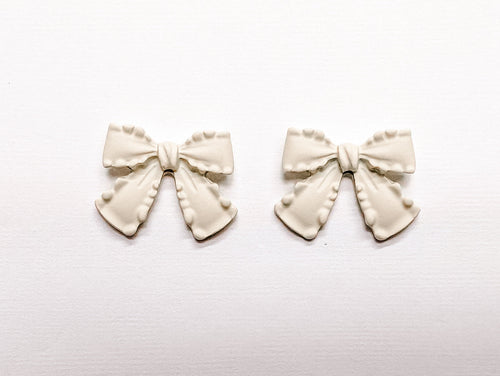 White bow earrings from Rooted Home Goods, featuring delicate design and charming white satin bows on silver hooks.