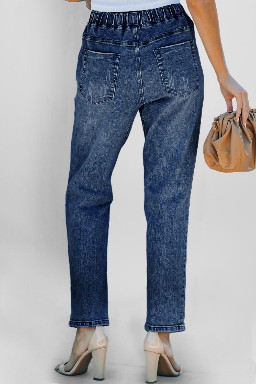 Dark blue distressed denim jogger with rounded pockets and gather detailing, designed for a casual, comfortable fit.