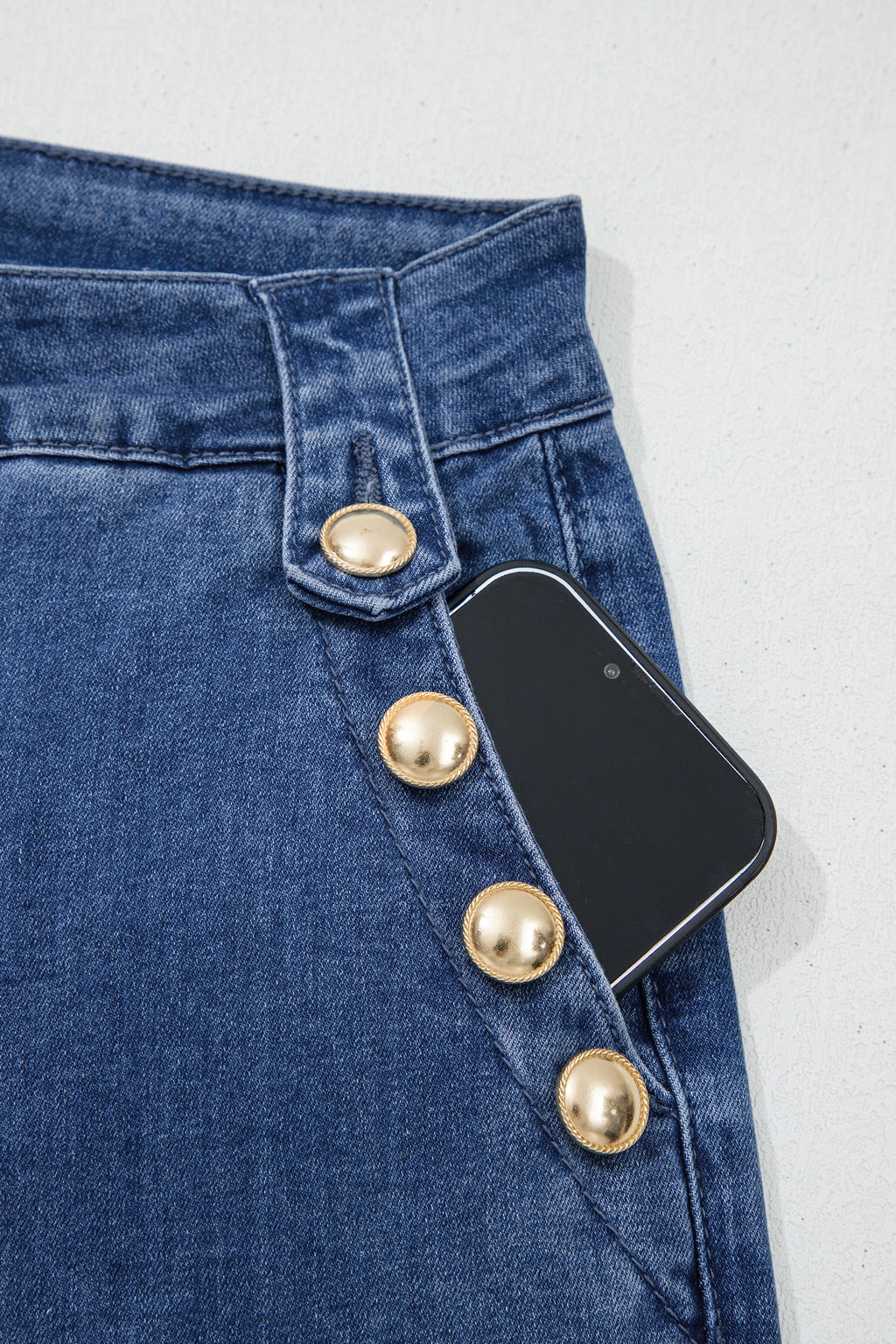 Dear-Lover Blue Ashleigh flare jeans with golden button detail, rolled edge design, and classic denim bottom style.