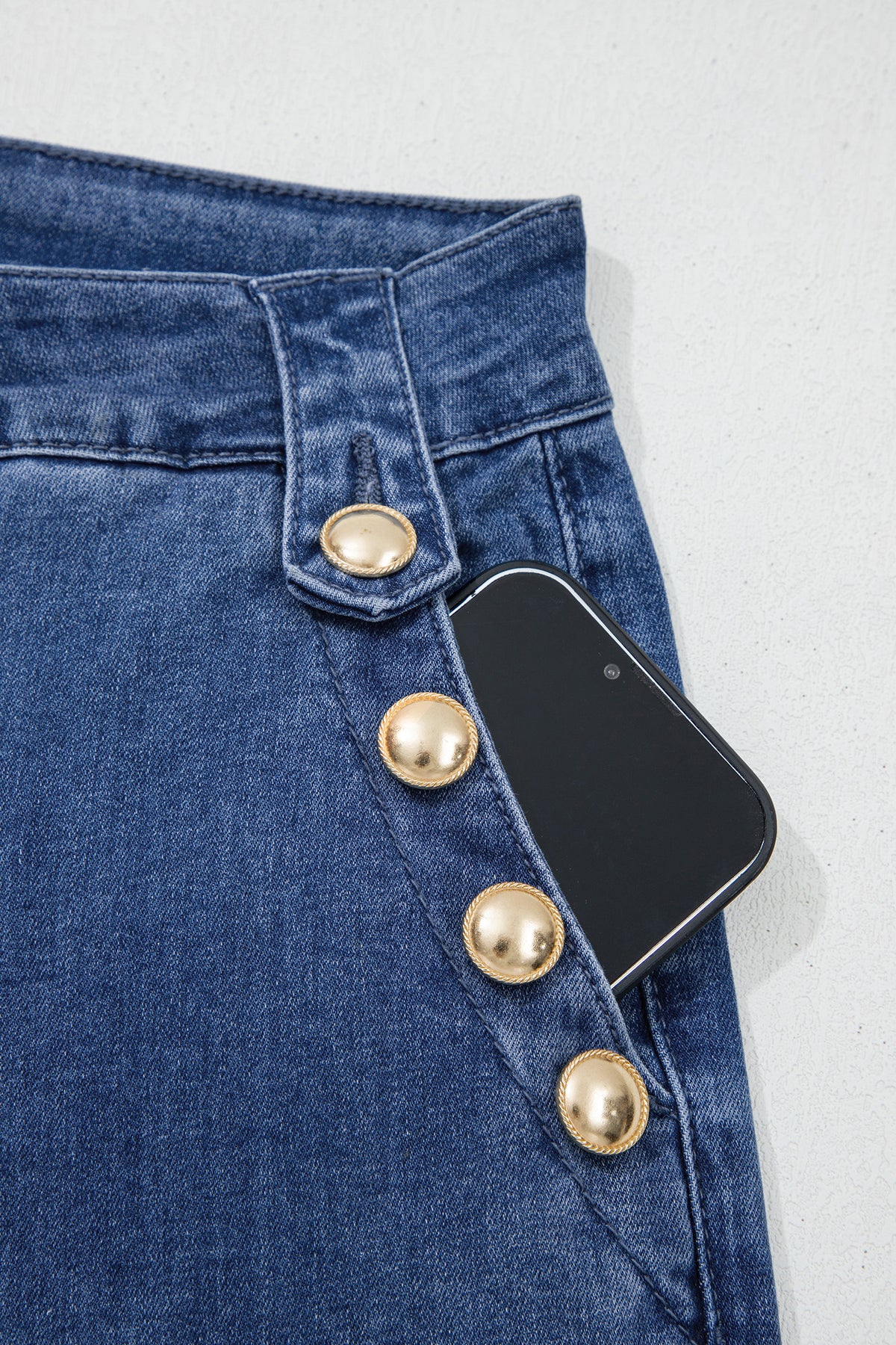 Dear-Lover Blue Ashleigh flare jeans with golden button detail, rolled edge design, and classic denim bottom style.