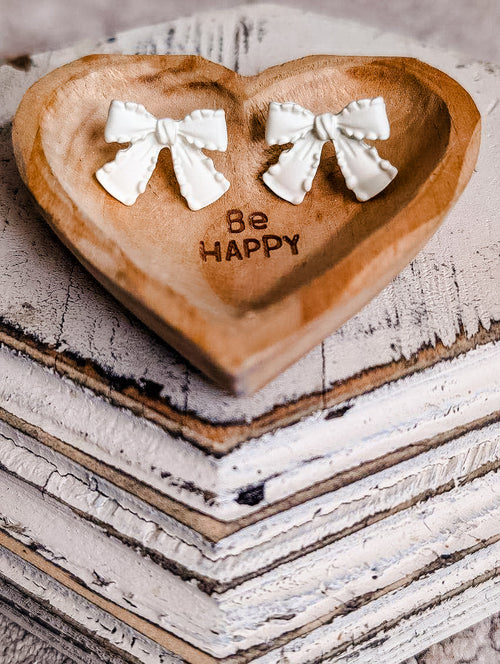 White bow earrings from Rooted Home Goods, featuring cute, dainty jewelry with delicate bow design on a plain background.