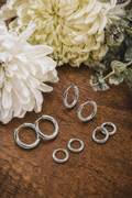 Set of four silver hoop earrings in various sizes, stylish jewelry from Rooted Home Goods with shiny, smooth finish.