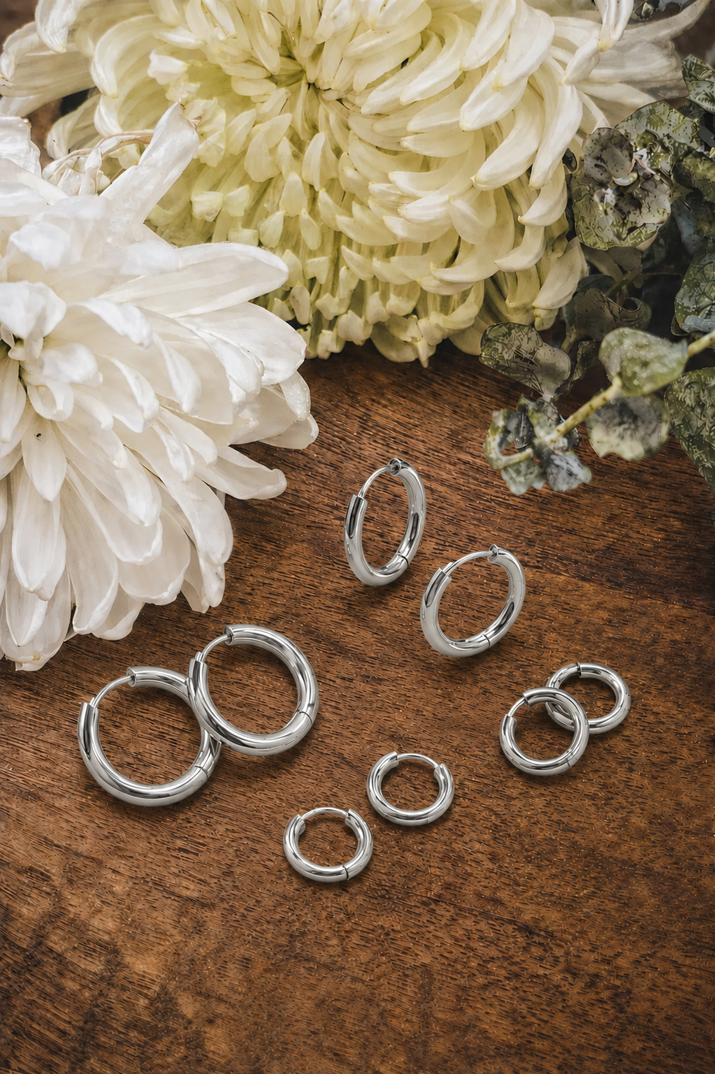 Set of four silver hoop earrings in various sizes, stylish jewelry from Rooted Home Goods with shiny, smooth finish.